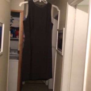 Simple black knee-length coattail dress with sophisticated back detailing.